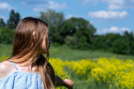 Happy smiling teenage girl having fun in nature. Ukrainian girl on yellow and blue background. Field and sky in colors of Ukrainian flag.の写真素材