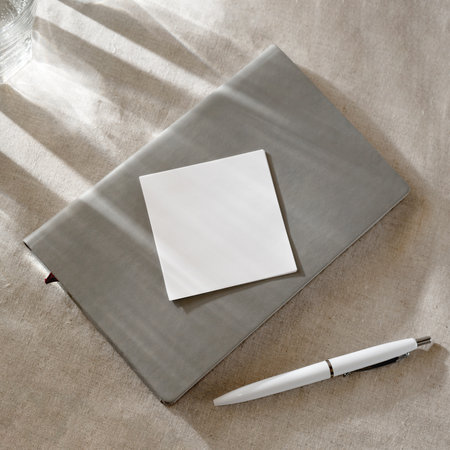 Notebook and empty paper card on a table with sunlight shadows, minimal business neutral brand template, copy spaceの写真素材