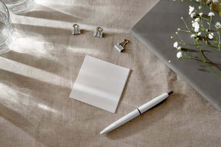 Blank paper card and sunlight shadows on a table, minimalist spring aesthetic workspaceの写真素材