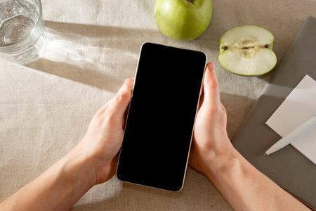 Mobile phone with empty black screen in a person's hands. Woman smartphone, template with copy spaceの写真素材