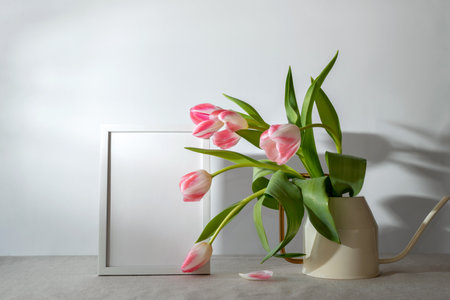 Empty frame and tulip bouquet on a light background. Aesthetic spring mock up or template with sunlifht shadows, copy spaceの写真素材