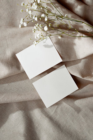 Minimal aesthetic business brand template, empty paper cards and flower on a neutral beige linen textile backgroundの写真素材