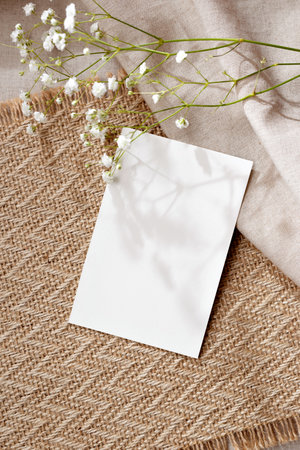 Blank paper card and flowers on a neutral warm beige background, subtle delicate aesthetic business branding, blog, invitation templateの写真素材