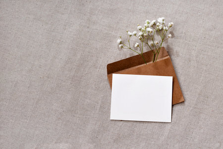 Aesthetic minimal brand template, holiday event or wedding invitation mock up with copy space, empty paper card, crafted envelope and flower on a neutral backgroundの写真素材
