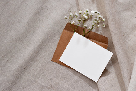 Empty paper card with mockup copy space, envelope, flowers on a neutral beige linen background, sophisticated subtle aesthetic business brand template, advertising, invitation or greeting cardの写真素材