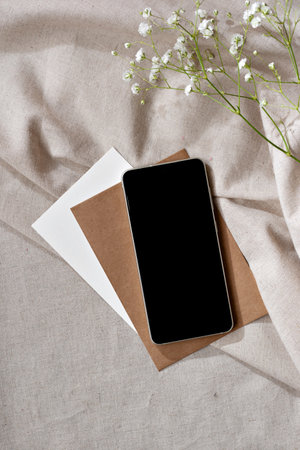 Elegant minimalist business, brand workspace template, mobile phone with empty screen copy space, papers on a neutral beige textile backgroundの写真素材