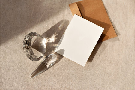 Elegant aesthetic business brand template, empty paper card with mock up copy space and glass crystals with reflections and sunlight shadows on a neutral beige table backgroundの写真素材