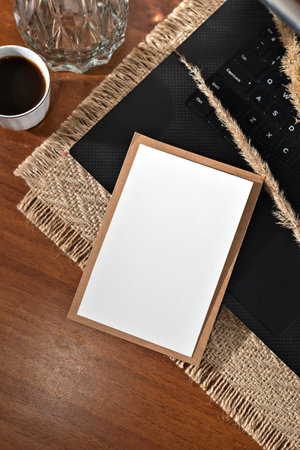 Aesthetic business branding mockup, blank paper card, laptop and cup of coffee on a brown wooden table background, template with copy cpaceの写真素材