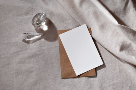 Minimalist lifestyle brand template, blank paper card with mock up copy space, glass crystals and sunlight shadows on a neutral beige backgroundの写真素材