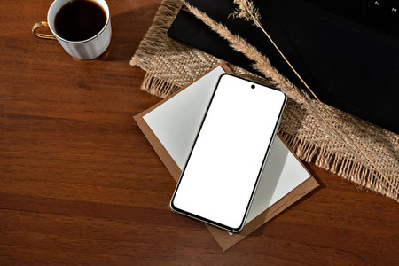 Mobile phone screen mockup, minimalist aesthetic business template with smartphone, cup of coffee and paper cards on a brown wooden table background, copy spaceの写真素材