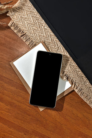 Mobile phone black screen mockup, minimalist aesthetic business template with smartphone and paper cards on a brown table background, copy spaceの写真素材