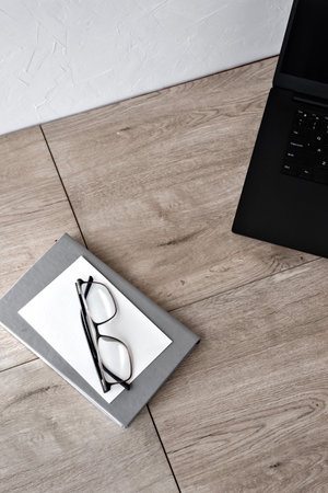 Minimalist elegant business brandind background, home office workspace, laptop, glasses, paper card, notebook on a wooden table, copy spaceの写真素材