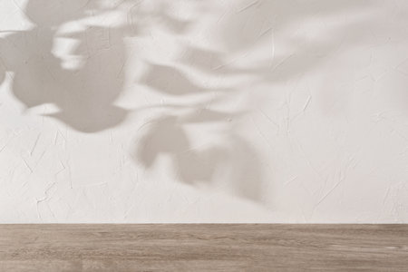 Beige textured concrete wall with aesthetic floral sunlight shadows, wooden floor, empty room elegant template, interior design background for business, branding advertisement, mockup with copy spaseの写真素材