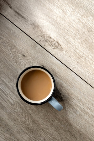 Hot coffee drink cup on a neutral beige wooden table with sunlight shadows, minimalist aesthetic morning breakfast or coffee break concept, flat lay, copy spaceの写真素材