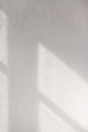Aesthetic geometric sunlight shadows on a white textured wall, window light silhouette background, template for home room interior productの写真素材