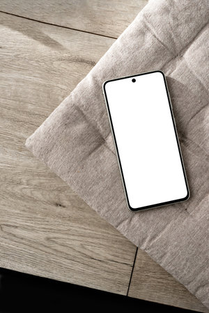 Mobile phone with empty screen mockup on a neutral beige interior pillow and wooden desk, minimalist aesthetic Scandinavian style business branding design template, copy spaceの写真素材