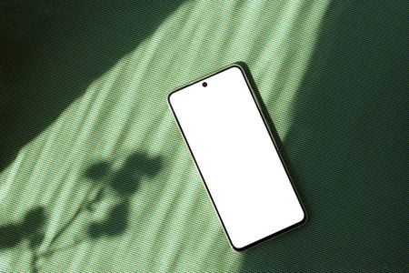 Minimalist summer business brand template, blank mobile phone screen mock up on bright green textile background with aesthetic floral sun light shadow, copy spaceの写真素材