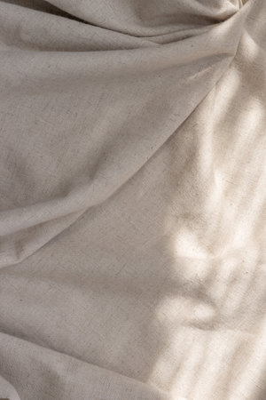 Draped beige linen cloth texture with a sunlight shadows, aesthetic bohemian wedding textile backgroundの写真素材
