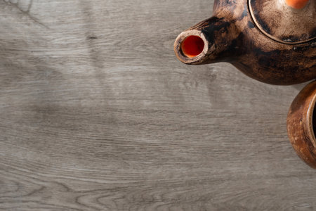 Minimalist tea ceremony background, pottery teapot and cup fragment closeup, wooden table with a sunlight shadows, copy spaceの写真素材