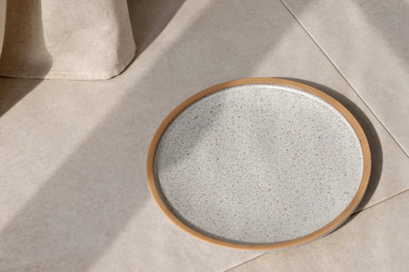 Empty gray ceramic plate on a beige stone table background with sun light shadow, aesthetic minimalist restaurant or cafe business brand template, copy spaceの写真素材