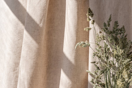 Aesthetic boho neutral floral background, abstract sunlight shadows on a beige linen curtain and meadow grass, elegant business, interior or wedding design templateの写真素材