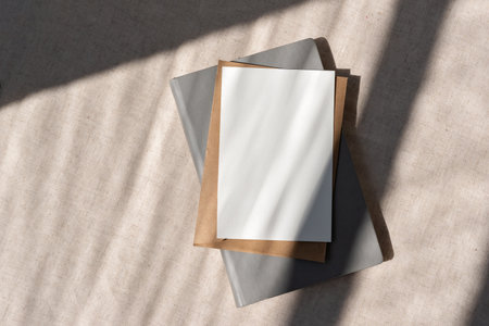 Blank paper card mock up, envelope, notebook on a neutral beige background with geometric abstract sunlight shadows, minimalist business brand template, copy spaceの写真素材