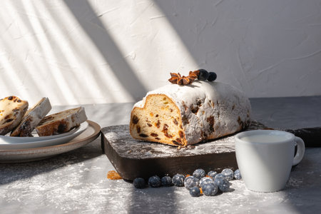 Lifestyle morning breakfast, sliced sweet cake with raisins, cup of milk on a table with aesthetic sun light raysの写真素材