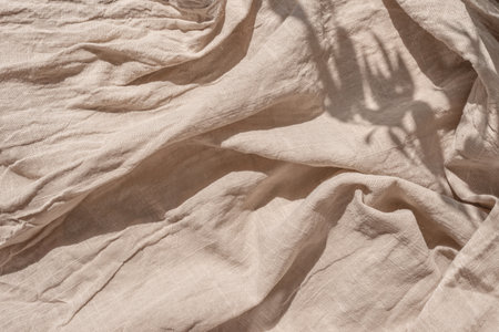 Abstract neutral background, crumpled draped linen fabric texture on a sun light with soft shadows,...