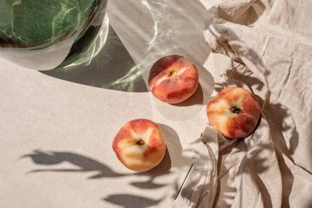 Ripe peaches on tan beige tabletop background with a abstract aesthetic sunlight shadows, summer fruit dietの写真素材