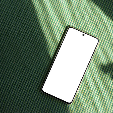 Smartphone empty screen mockup on a green background with abstract sun light shadowsの写真素材