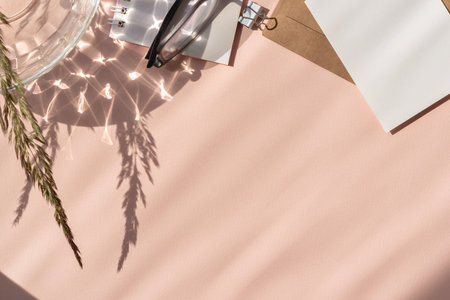 Aesthetic feminine business brand flat lay, paper cards, glasses, crystal glass and floral sunlight shadow on a peach beige neutral background, copy spaceの写真素材