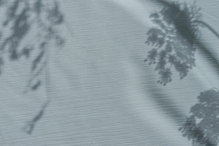 Aesthetic floral neutral pastel blue background with wildflower sunlight shadows on fabric texture....