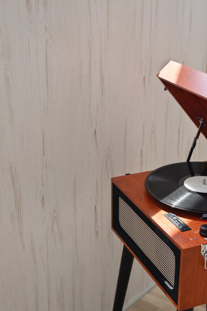 Brown retro wooden turntable with dusty vinyl record indoor on neutral beige wall background, copy space. Modern trend, digital vinyl player, home interior. Nostalgic music style conceptの写真素材
