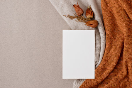 Aesthetic autumn wedding invitation, business brand design template, flat lay. Blank paper card mock up, fall leaves on neutral beige and bright ginger, orange knitted textile background.の写真素材