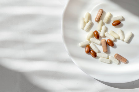Minimal lifestyle aesthetic medicine concept. White and brown pills and capsules on white plate and...