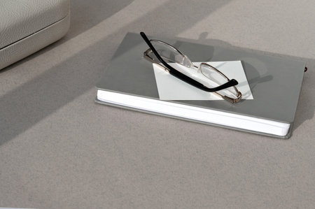 Minimal business background, notepad, glasses, paper card on neutral beige table.の写真素材