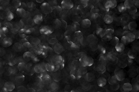 Abstract shiny festive texture with defocused silver glitter lights bokeh on black background.