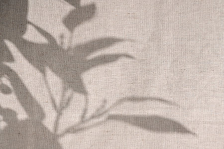 Abstract floral sunlight shadow silhouette on neutral beige linen cloth texture background. Minimal...