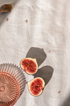 Aesthetic autumn neutral background, cut fig fruit on neutral beige linen cloth background with...