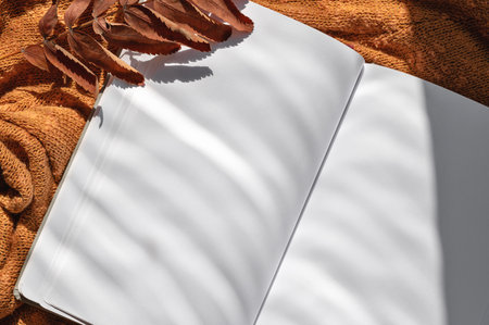 Open notebook with empty sheets mockup, brown fall leaves on knitted textured background with...