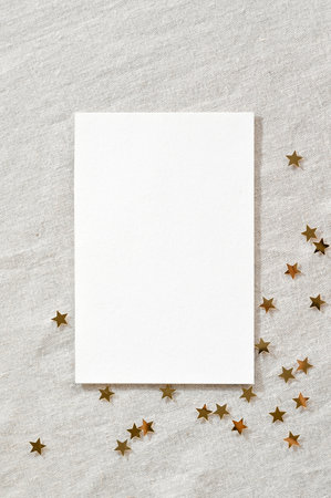 Minimalist festive business brand template for New Year holiday announcement or advertising flyer. Blank paper card mockup, gold star confetti on neutral beige linen texture background.の写真素材