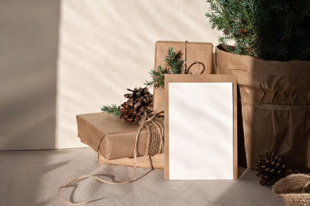 Blank paper card mockup, envelope, crafted gift boxes, juniper tree on neutral beige linen table cloth background with harsh sunlight shadows. Lifestyle Christmas postcard or invitation template.の写真素材