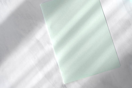 Minimal aesthetic business branding background with pastel green paper on gray marble table...