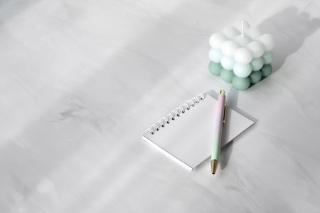 Notebook with blank sheets and pen on white neutral marble table background with soft sunlight shadows, lifestyle minimal workspace, planning concept.の写真素材