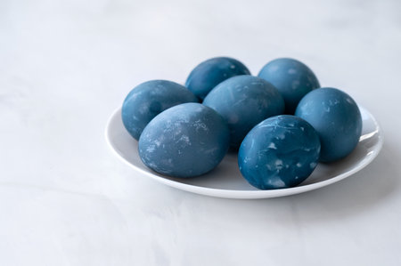 Blue colored Easter eggs on white table on neutral marble table background, traditional Easter...