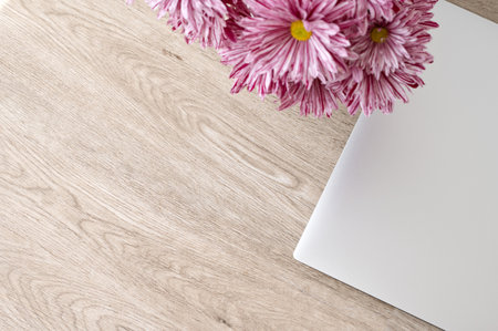 Aesthetic minimalist background for business branding, gray laptop and pink daisy flowers bouquet on neutral beige wooden table, top view, empty copy space.の写真素材