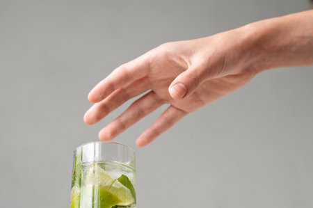 Persons hand reaching for glass with mojito cocktail drink.の写真素材