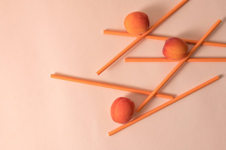 Drinking straws and apricot fruits on peachy pastel background, summer food and drink concept.の写真素材