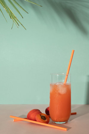 Summer fruit cocktail drink on turquoise blue background with tropical palm leaf sunlight shadow, empty copy space, retro aesthetic.の写真素材
