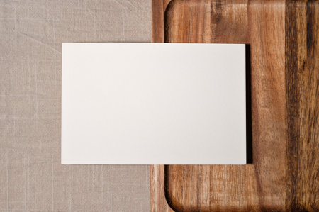 Blank paper card mockup on brown wooden tray and beige linen tablecloth background, minimal neutral business template with copy space.の写真素材